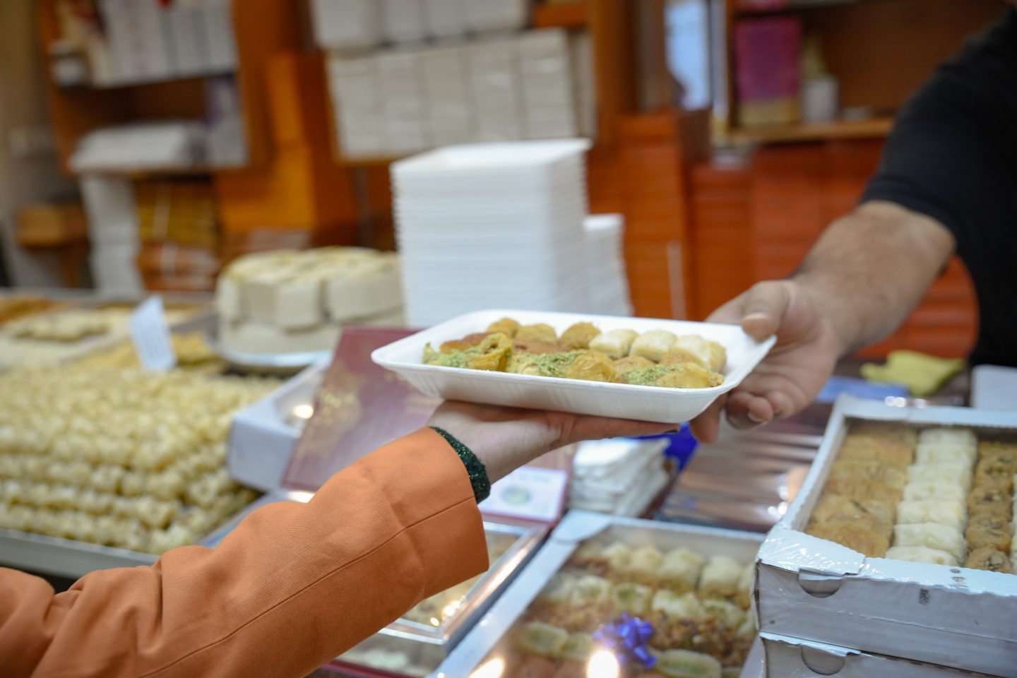 A filled tray of assorted sweets handed across the counter